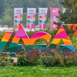 Das Laga-Logo als bunte Großbuchstaben im Wiesenpark, dahinter Fahnen mit der Aufschrift Herzlich Willkommen
