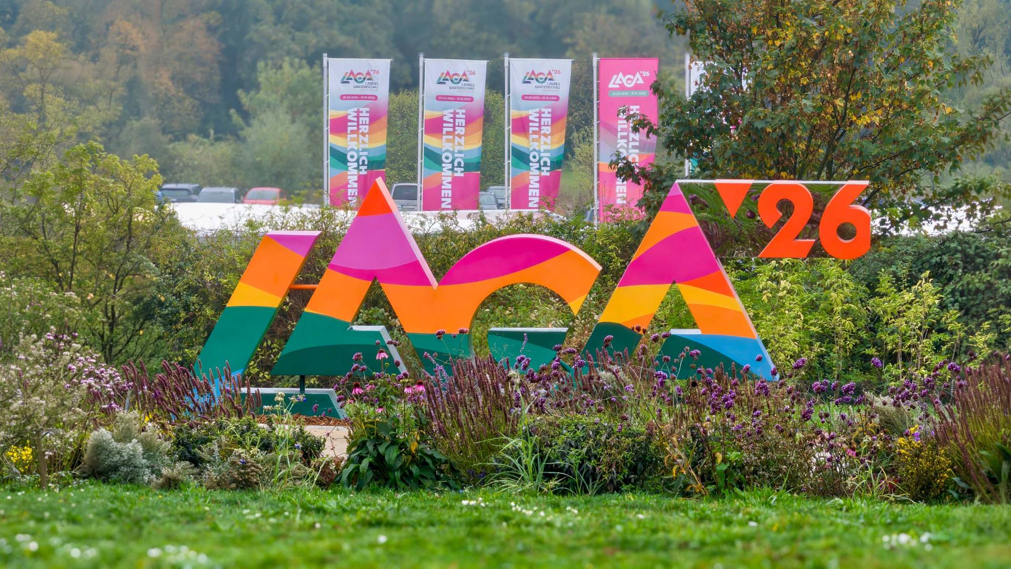 Das Laga-Logo als bunte Großbuchstaben im Wiesenpark, dahinter Fahnen mit der Aufschrift Herzlich Willkommen